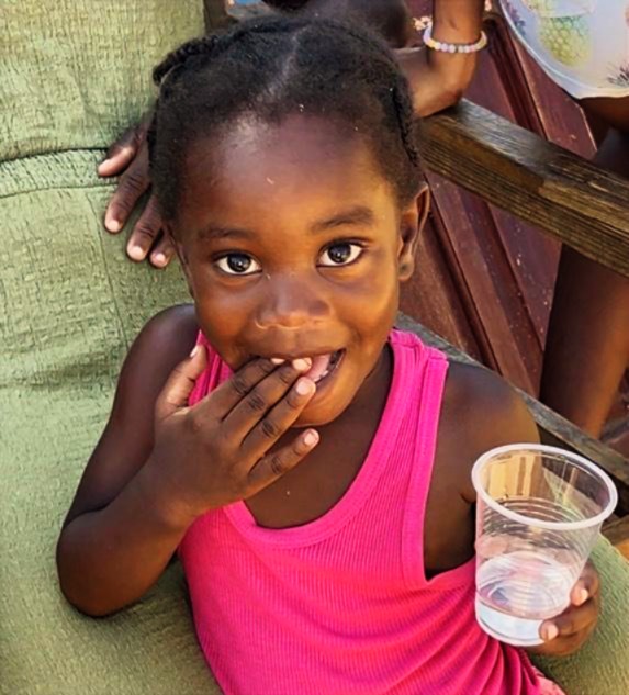 A child in Jamaica holding a cup of clean water provided through Healthy Souls International outreach